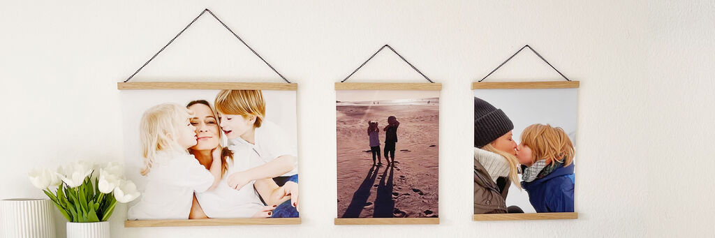 Na ścianie wiszą trzy plakaty z listwą ze zdjęciami rodzinnymi.